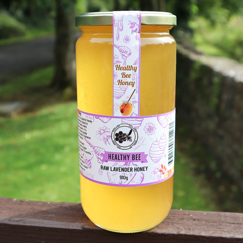 Jar of Healthy Bee Raw Lavender Honey on a wooden surface with a natural background